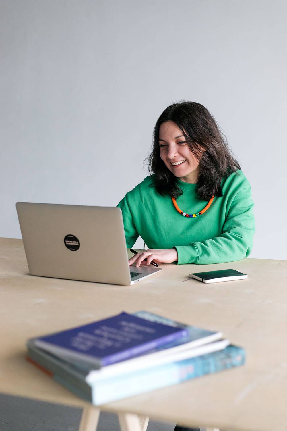 Anna Kokalanova sitting on a table and working on a computer.