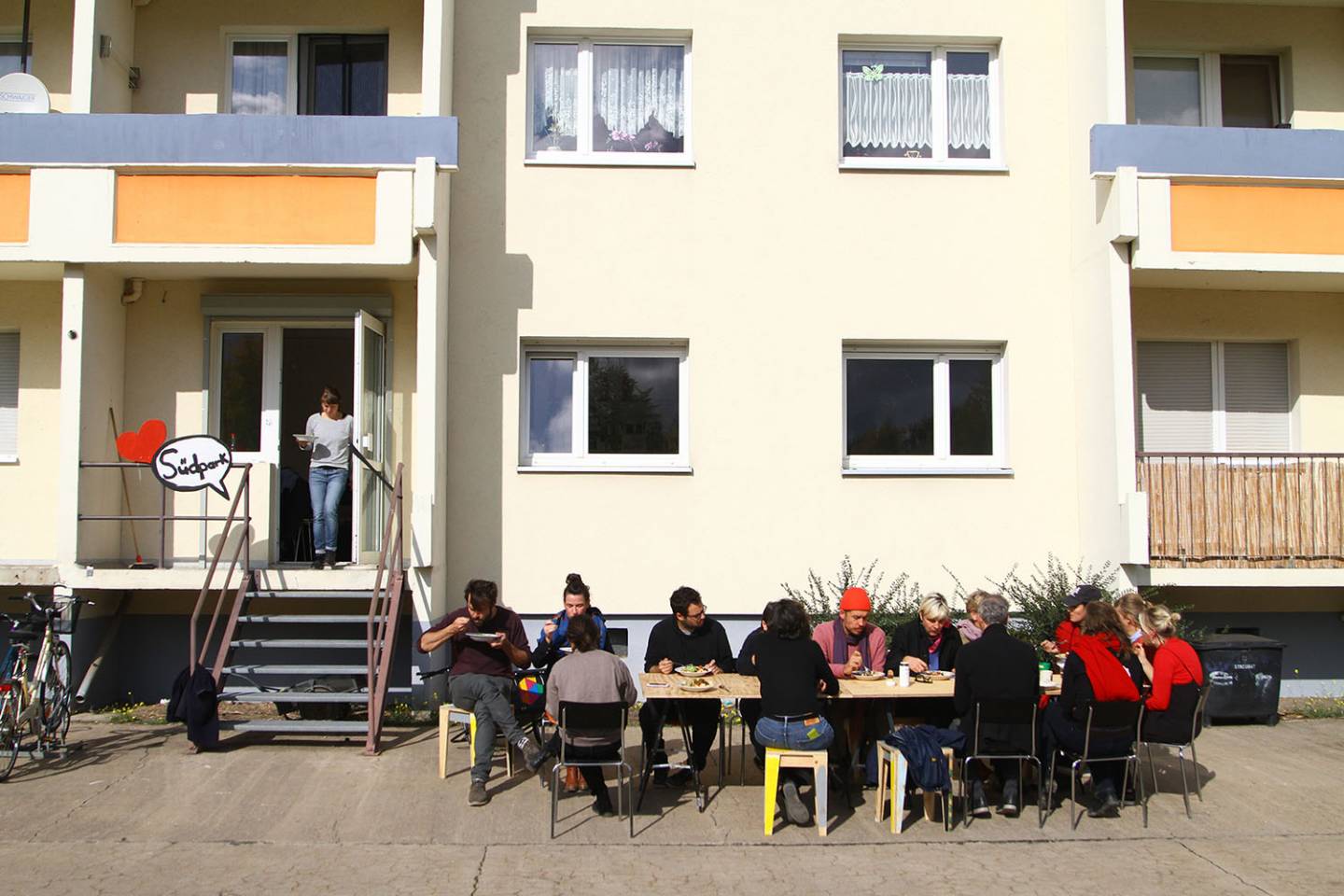 People sitting on a table in front of a GDR block and having lunch.