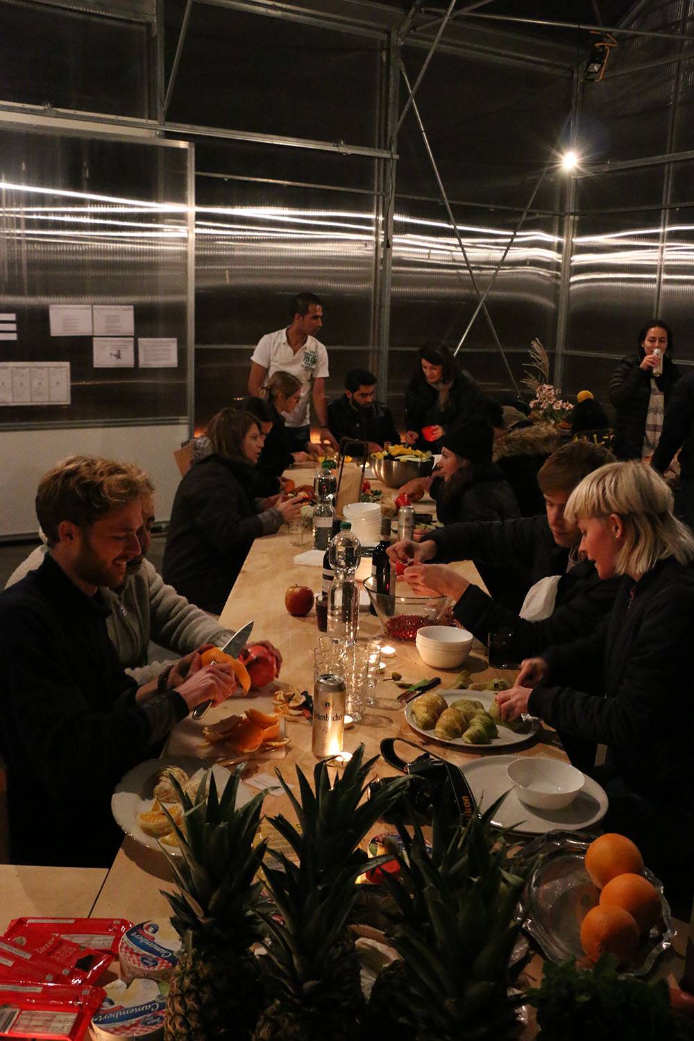 People sitting on a long table and having dinner.